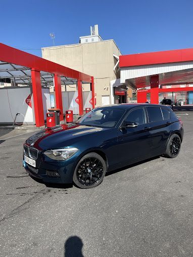 Un coche negro está aparcado delante de una gasolinera.