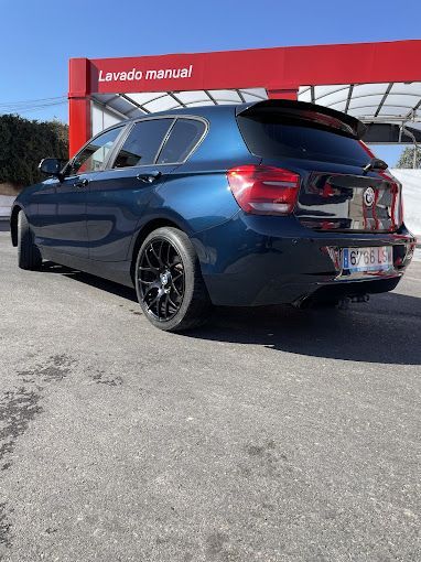 Un coche azul está aparcado delante de un lavadero de coches.