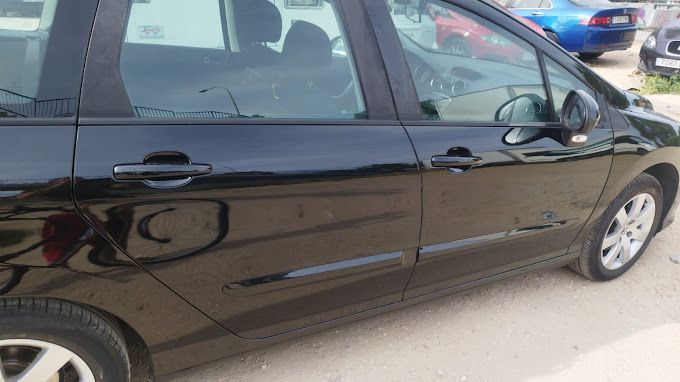 Un coche negro está estacionado al costado de la carretera.