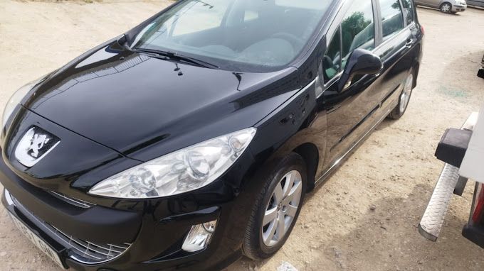 Un Peugeot 308 negro está estacionado en un terreno de tierra.
