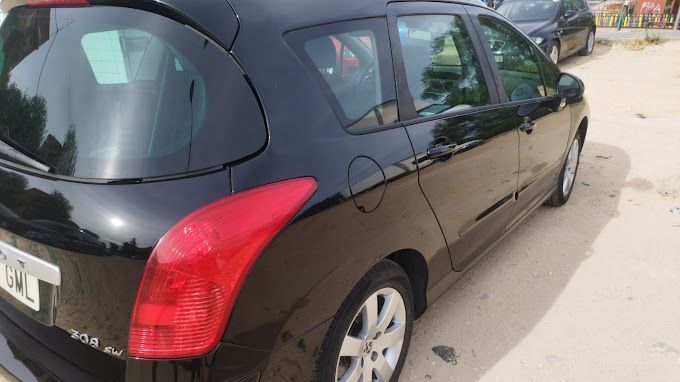 Un coche negro con una luz trasera roja está estacionado en un estacionamiento.