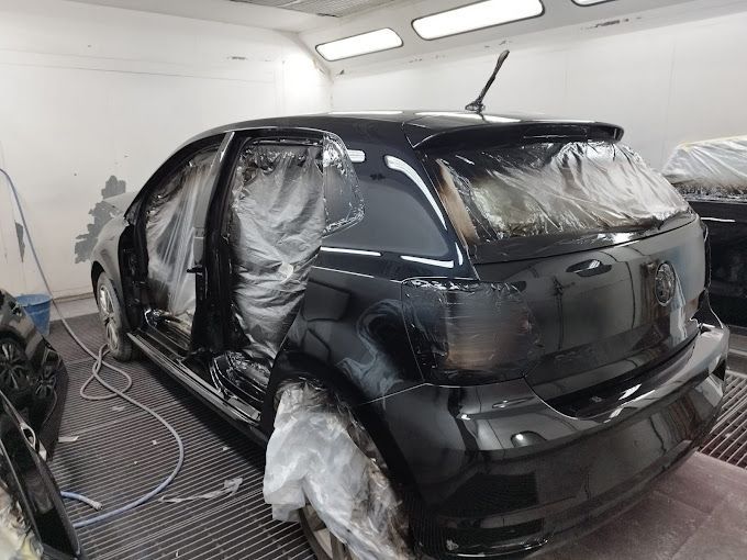 Se está pintando un coche negro en una cabina de pintura.