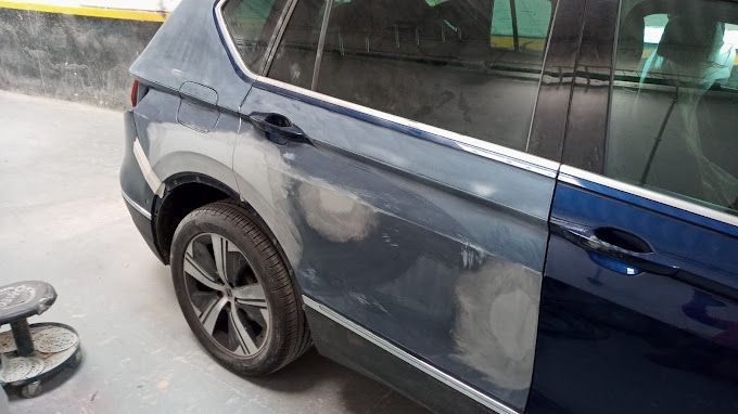 Se está pintando un coche azul en un garaje.