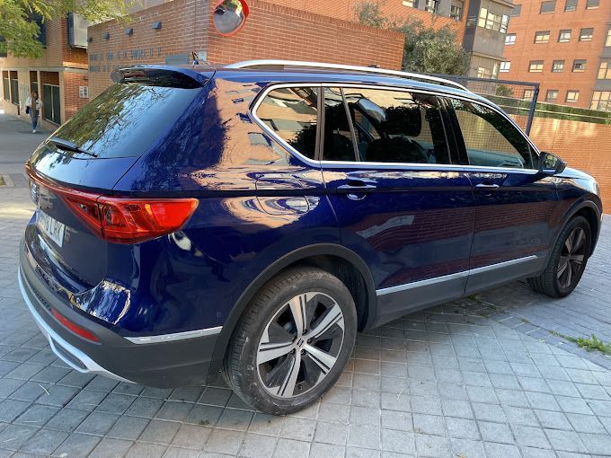 Una camioneta azul está estacionada en una acera frente a un edificio.