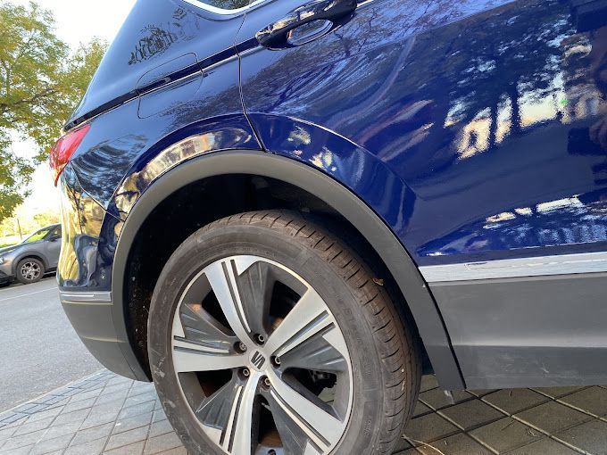 Un coche azul está aparcado al costado de la carretera.