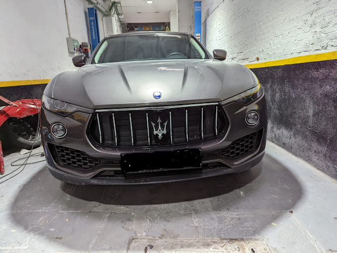 Un Maserati gris está aparcado en un garaje.