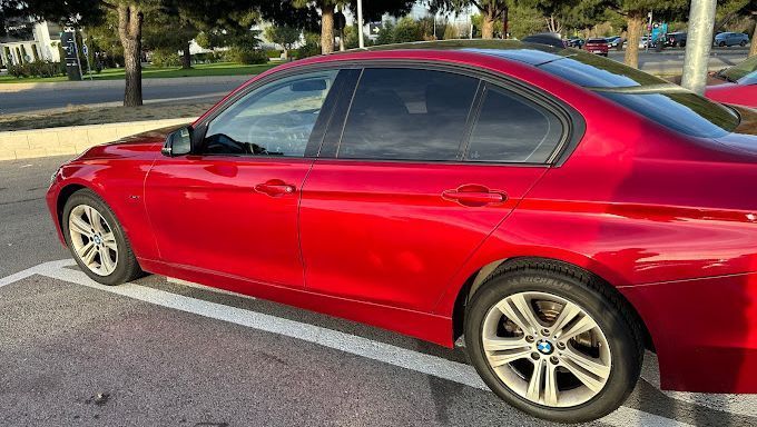 Un BMW Serie 3 rojo está estacionado en un estacionamiento.