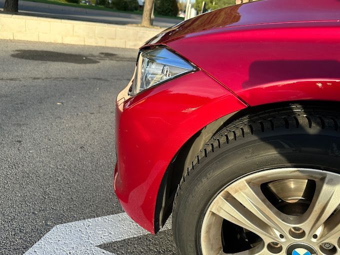 Un BMW rojo está estacionado al costado de la carretera.