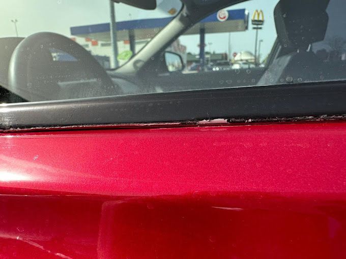 Un coche rojo está aparcado delante de un McDonald's.