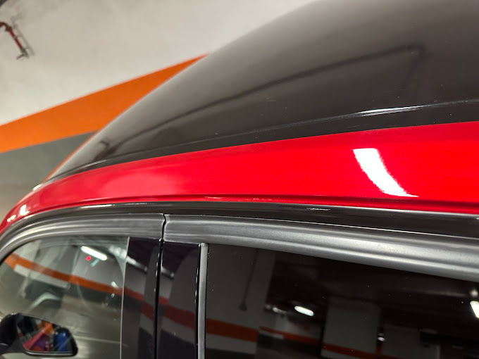 Un coche rojo con techo negro está aparcado en un garaje.