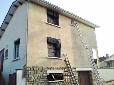 Traitement de l'humidité en façade d'une maison en cours montrant une partie saine et une partie sombre