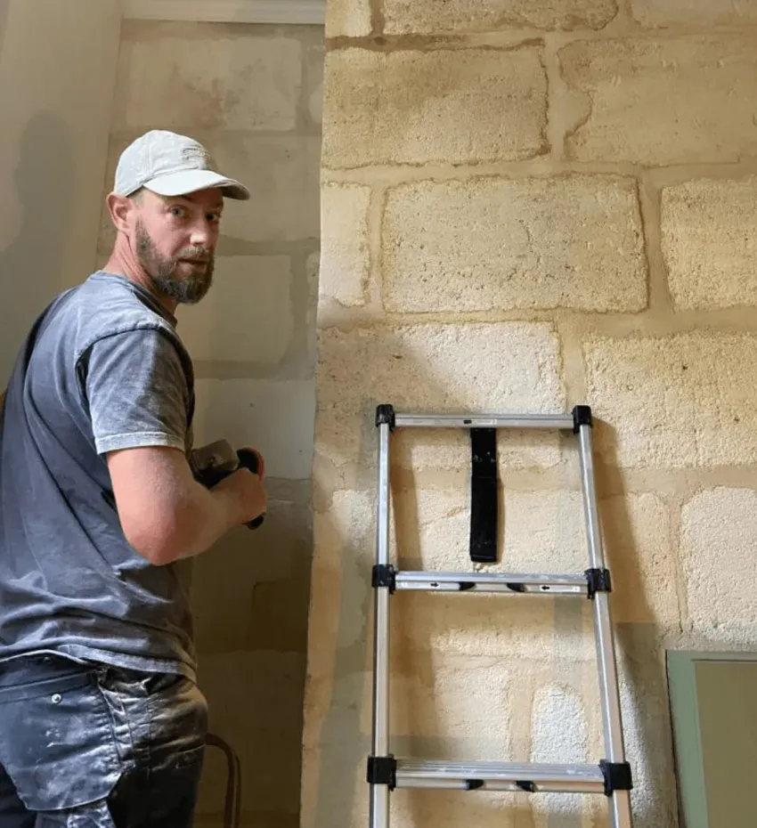 Ouvrier peignant un mur à côté d'une échelle dans une pièce inachevée