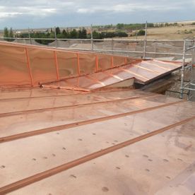 Techo de cobre con andamios que refleja la luz del sol.