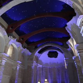 Interior de un edificio de piedra con techos abovedados y un cielo estrellado pintado en el techo.
