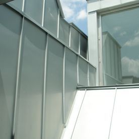 Exterior de edificio de metal gris con paneles verticales y ventana.