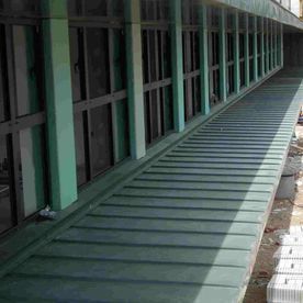 Rampa de metal verde al lado de un edificio con ventanas oscuras.