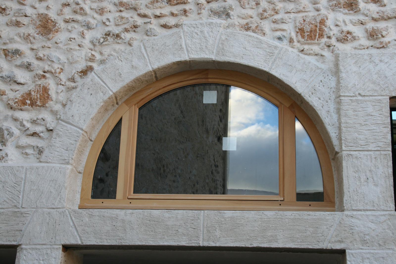Fenêtre demi-lune en bois avec encadrements en fausses pierres