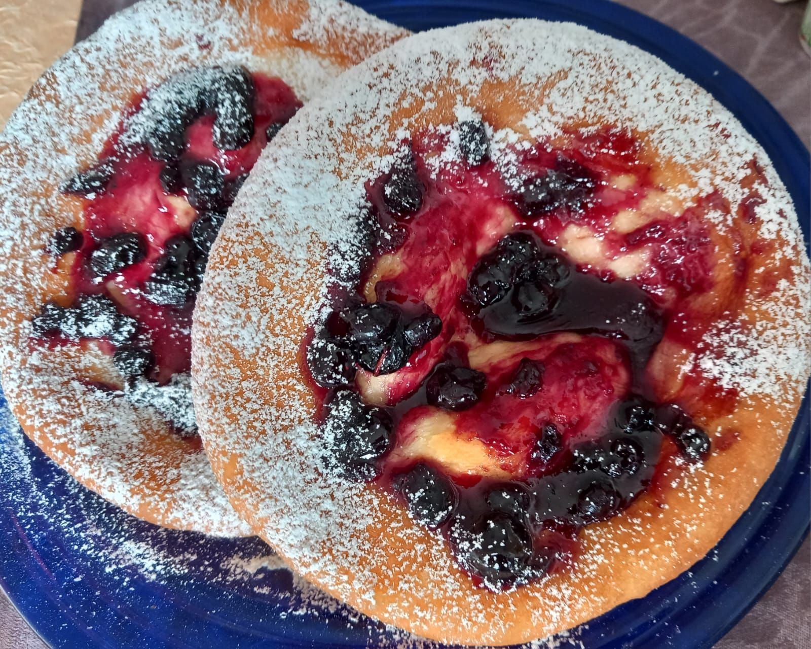 Dos panqueques con bayas y azúcar en polvo en un plato azul