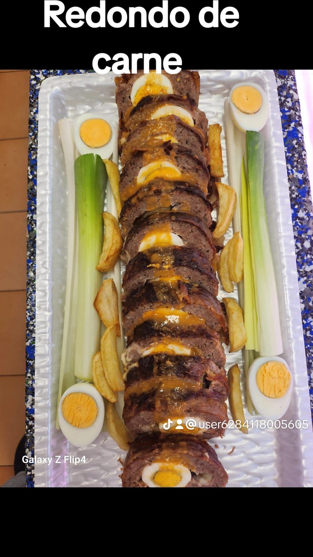 Una bandeja de comida con carne, huevos, patatas y cebollas sobre una mesa.