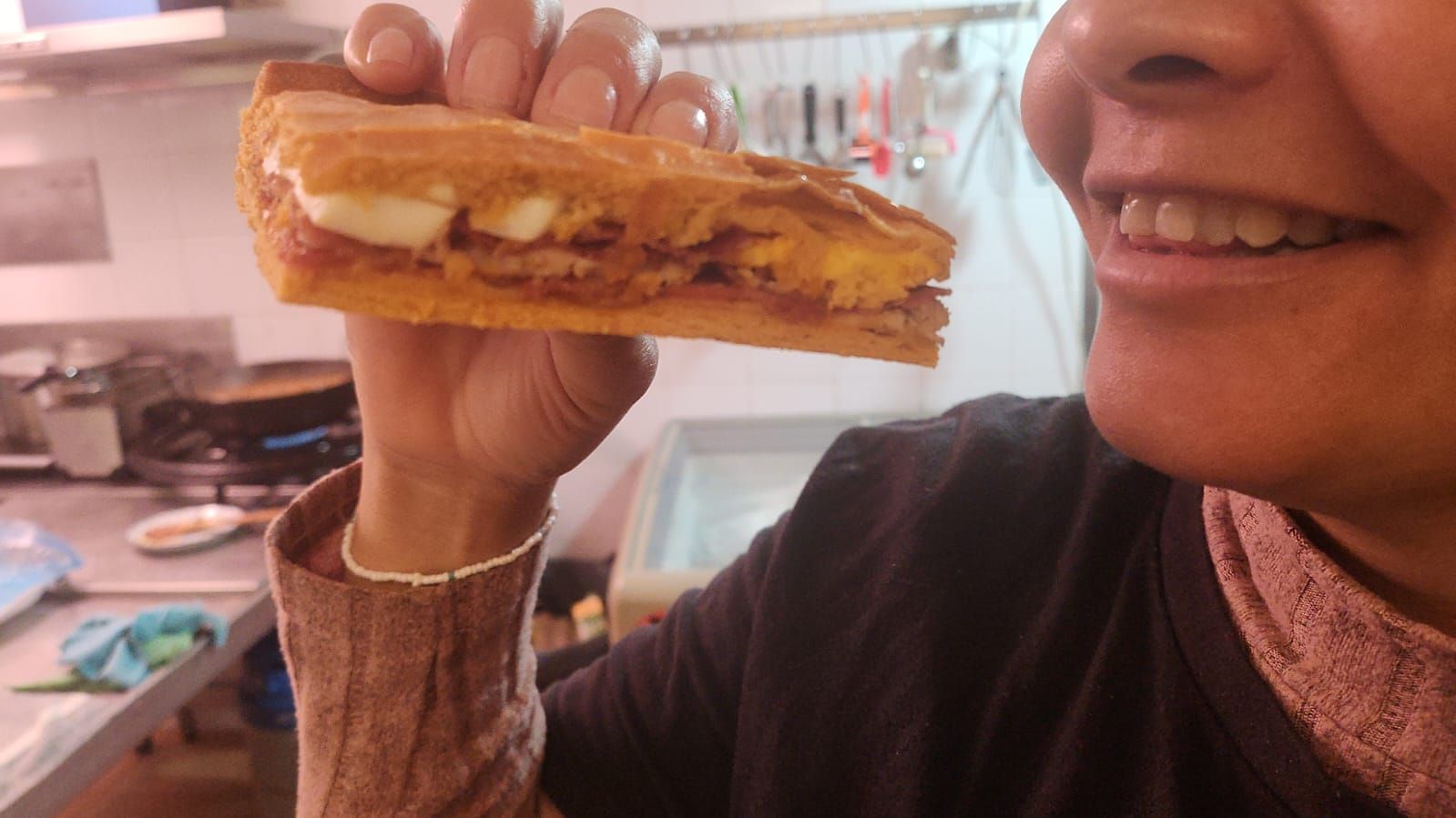 Una mujer sostiene una rebanada de sándwich en su mano.