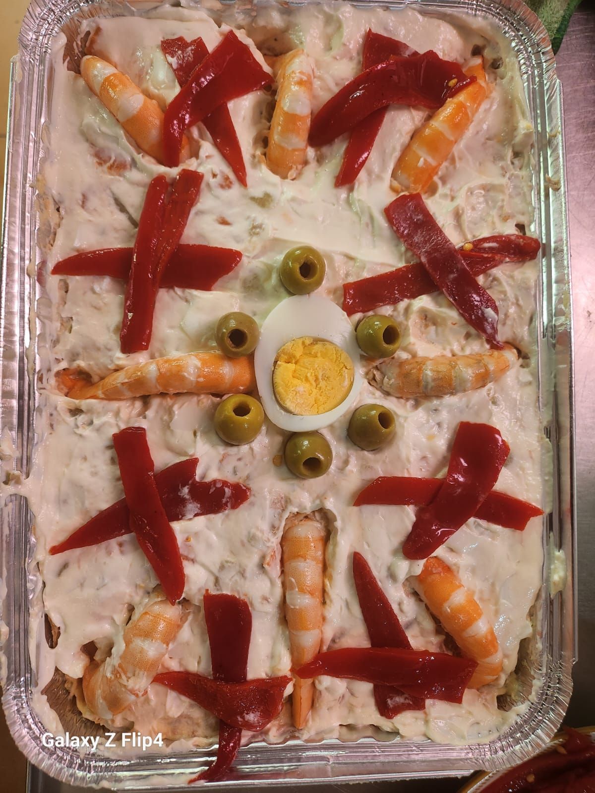 Una bandeja de comida con camarones, huevos, aceitunas y pimientos rojos.