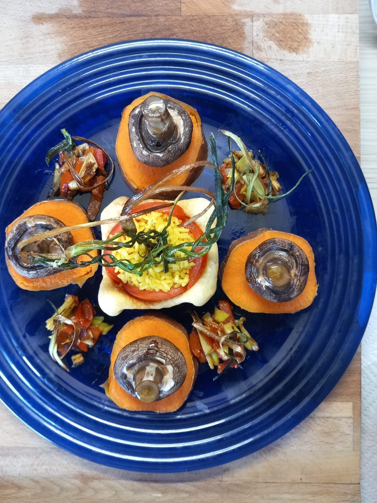Un plato azul cubierto con zanahorias, tomates y champiñones.