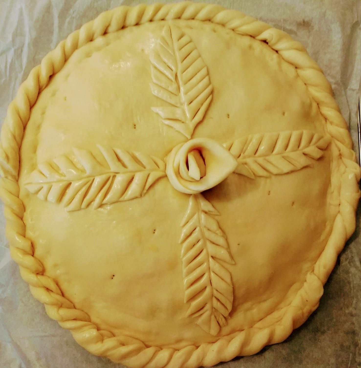 Un pastel con una flor y hojas encima está sobre una mesa.