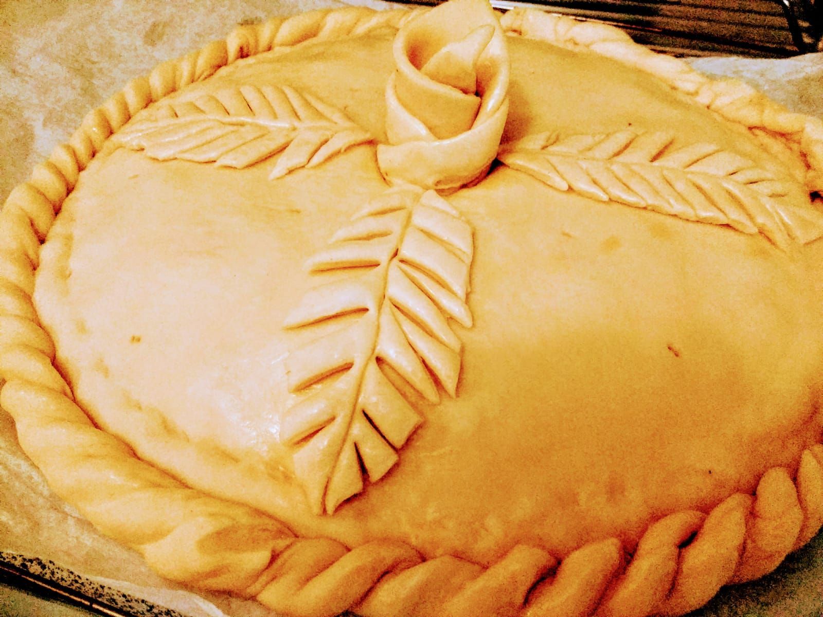 Un pastel con una flor y hojas encima está sobre una mesa.