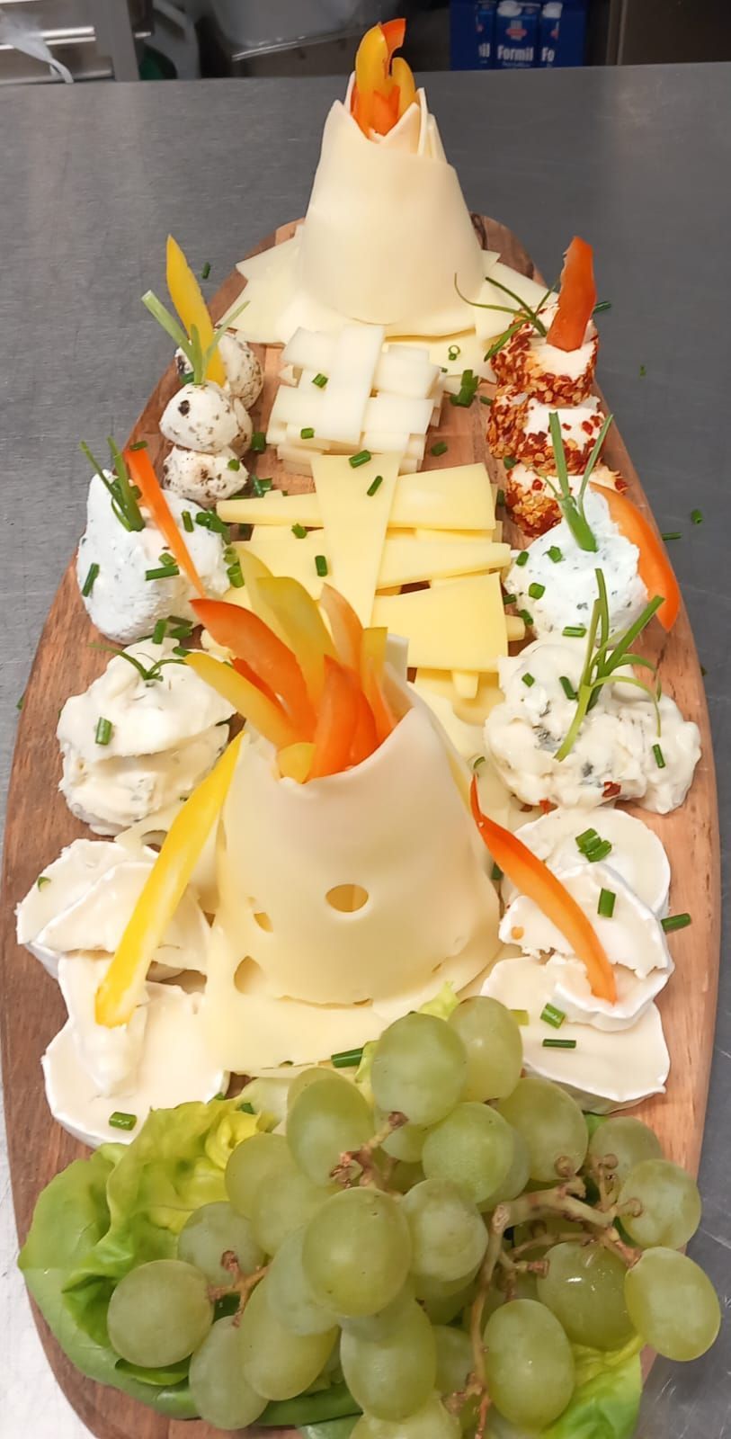 Una tabla de cortar de madera cubierta con queso, uvas y zanahorias.