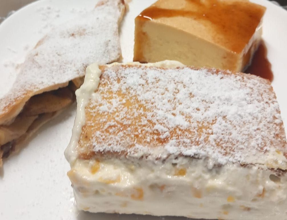 Un plato blanco cubierto con tres postres diferentes cubiertos de azúcar en polvo.