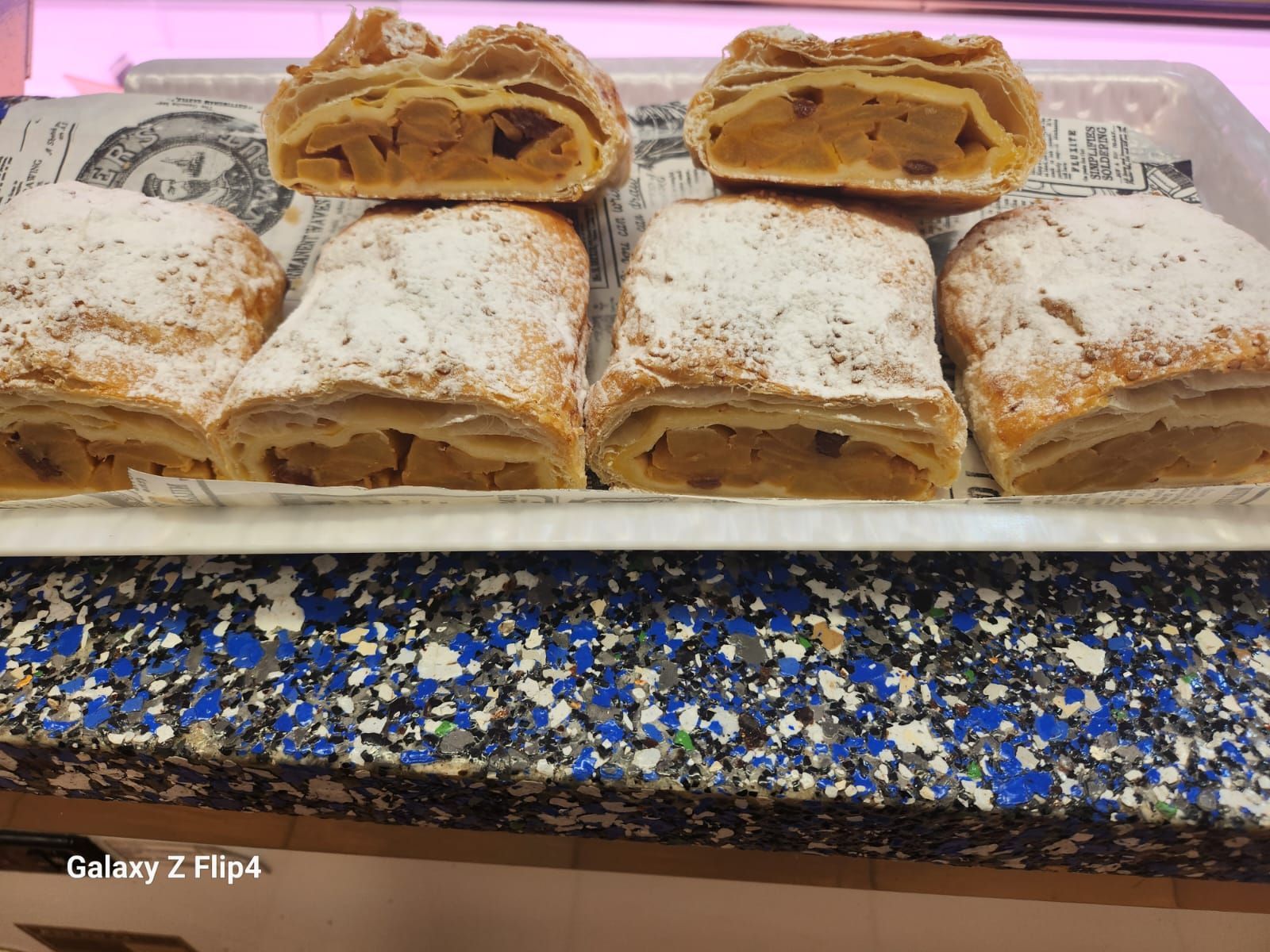 Una bandeja de strudels de manzana cubiertos de azúcar en polvo sobre un mostrador.