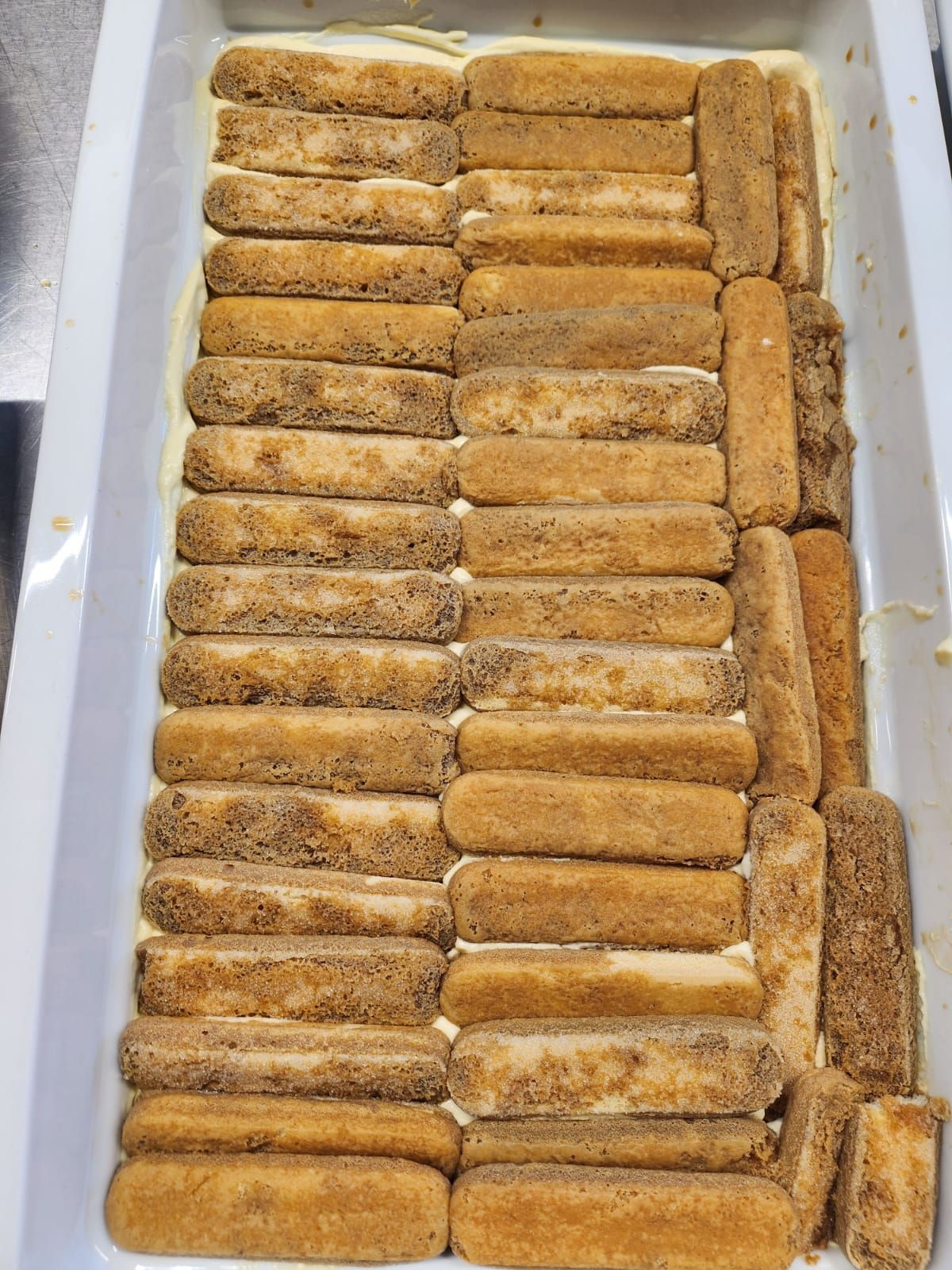 Una cazuela rellena de galletas de tiramisú y crema.