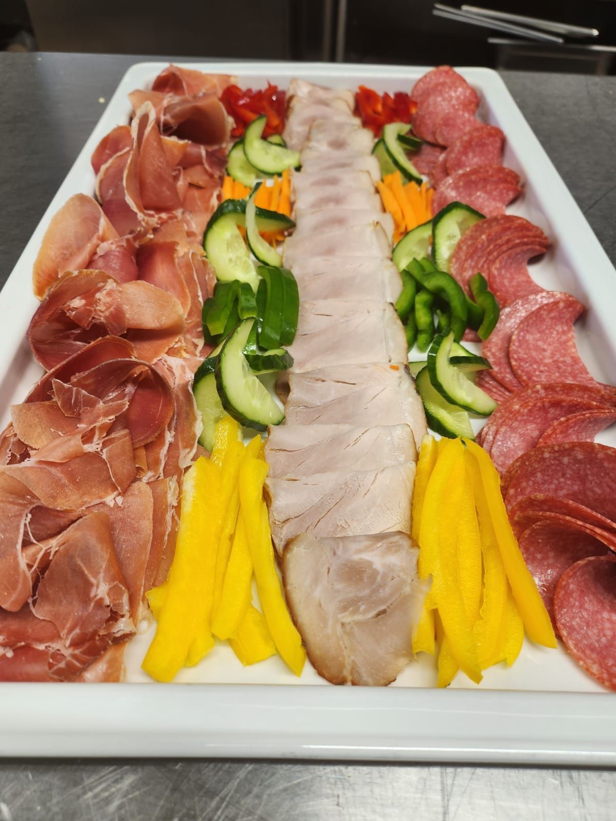 Una bandeja blanca llena de carne y verduras sobre una mesa.