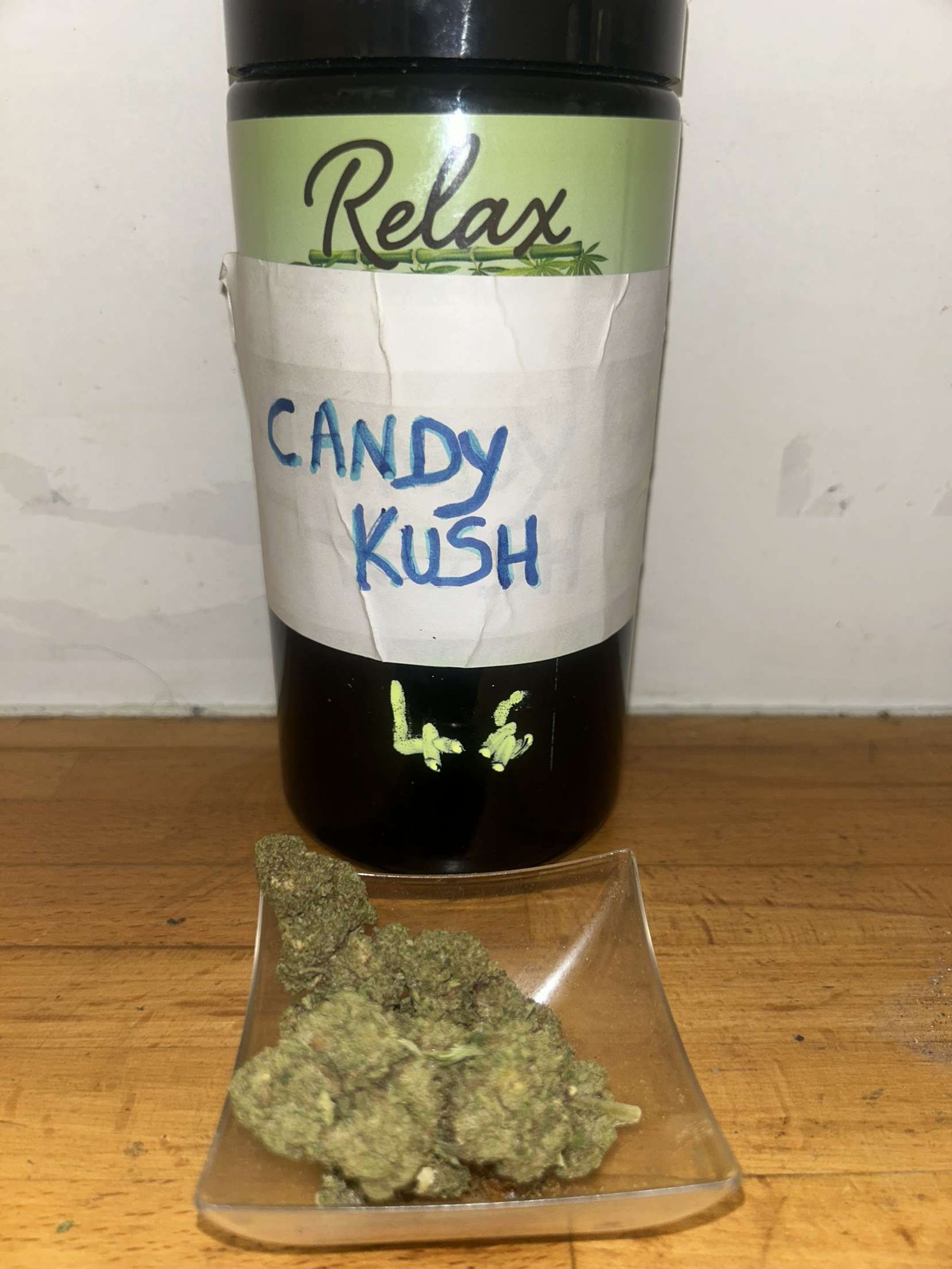 Un contenant de Candy Kush est posé sur une table en bois.