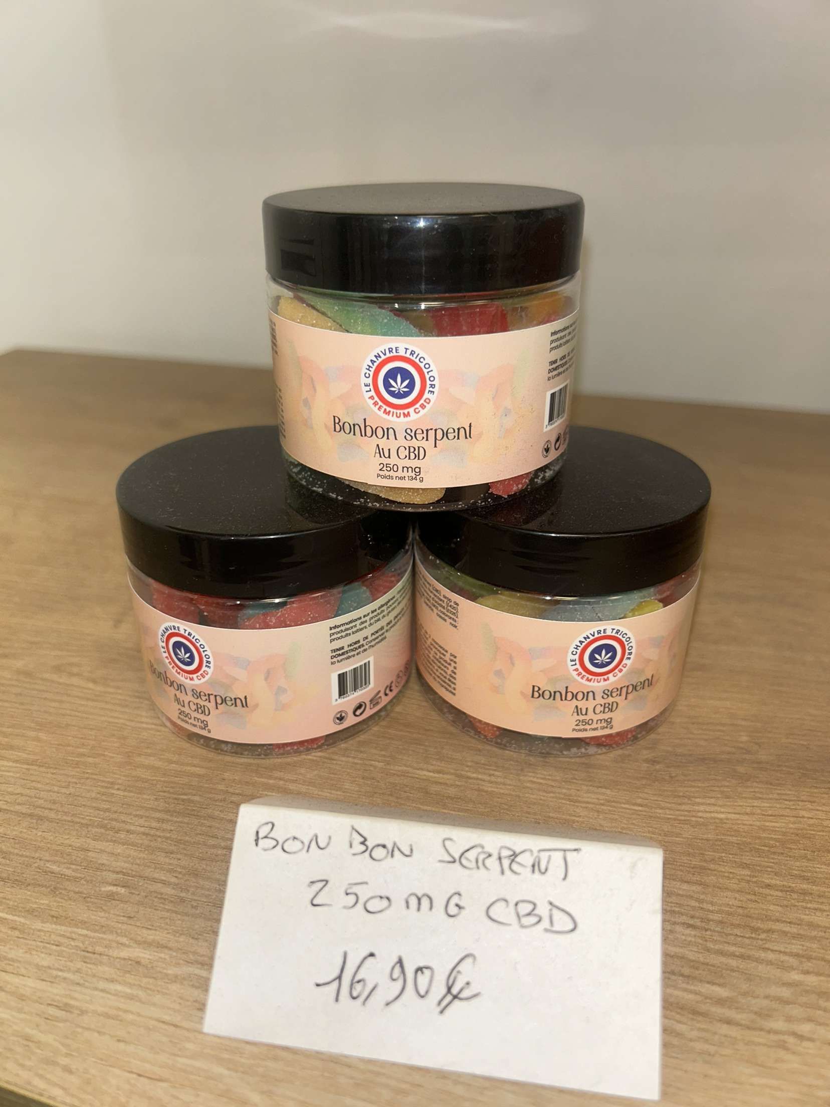 Trois pots d'oursons en gélatine sont empilés les uns sur les autres sur une table en bois.