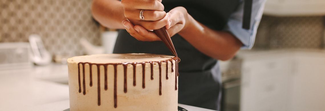 Una persona está decorando un pastel con gotas de chocolate.