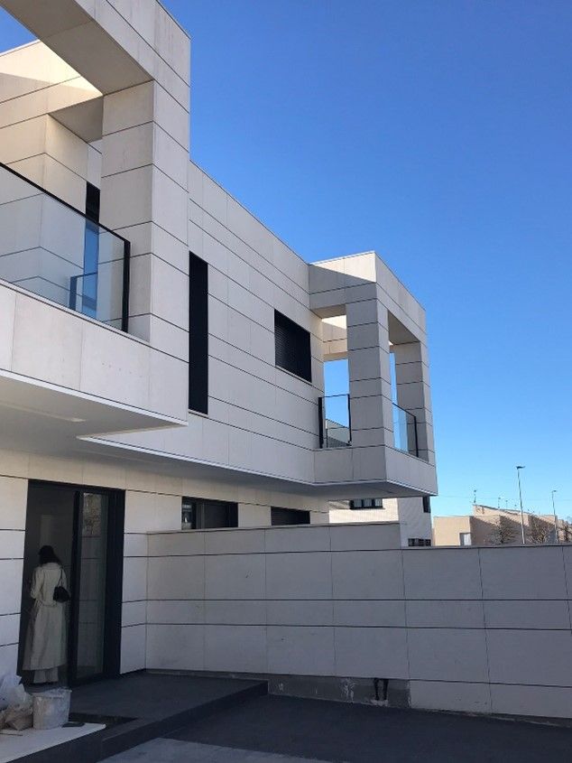 Edificio moderno de color blanco con balcones de cristal que se recortan contra un cielo azul despejado