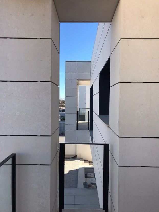 Vista arquitectónica exterior: fachada de piedra blanca con aberturas enmarcadas hacia el cielo.