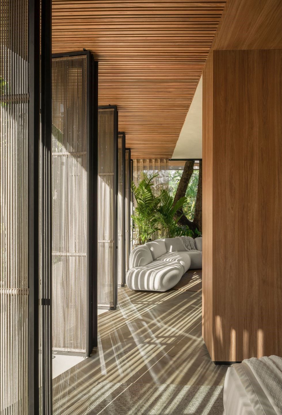 Interior moderno con techo y paredes de madera, luz solar que se filtra a través de paneles texturizados.