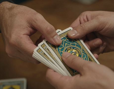 Manos abanicando cartas, con los dorsos estampados en azul y dorado a la vista.