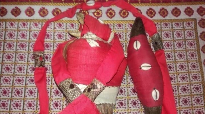 Muñecas de tela roja con atuendos estampados y un accesorio rojo a juego sobre un fondo estampado.