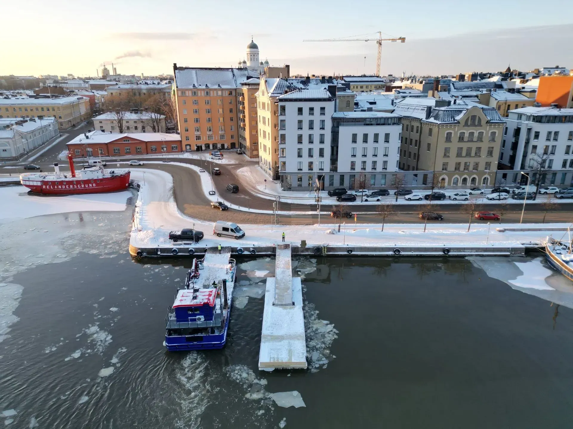Luminen ranta-alue, jossa telakoituneita veneitä rakennusrivin vieressä auringonlaskun aikaan
