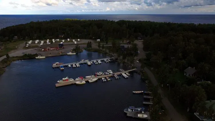 Ilmakuva venesatamasta, jossa veneet ovat telakoituna tummansinisellä järvellä hämärässä, puiden ympäröimänä.