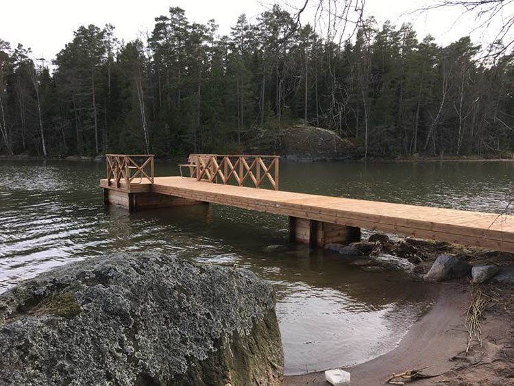 Puinen laituri kaiteineen ulottuu rauhallisen järven yli metsäisen rannan vieressä