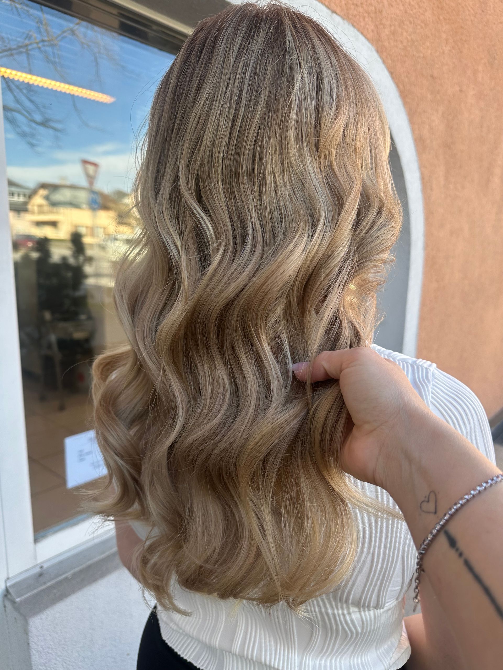 Une femme de dos au cheveux blond et ondulés