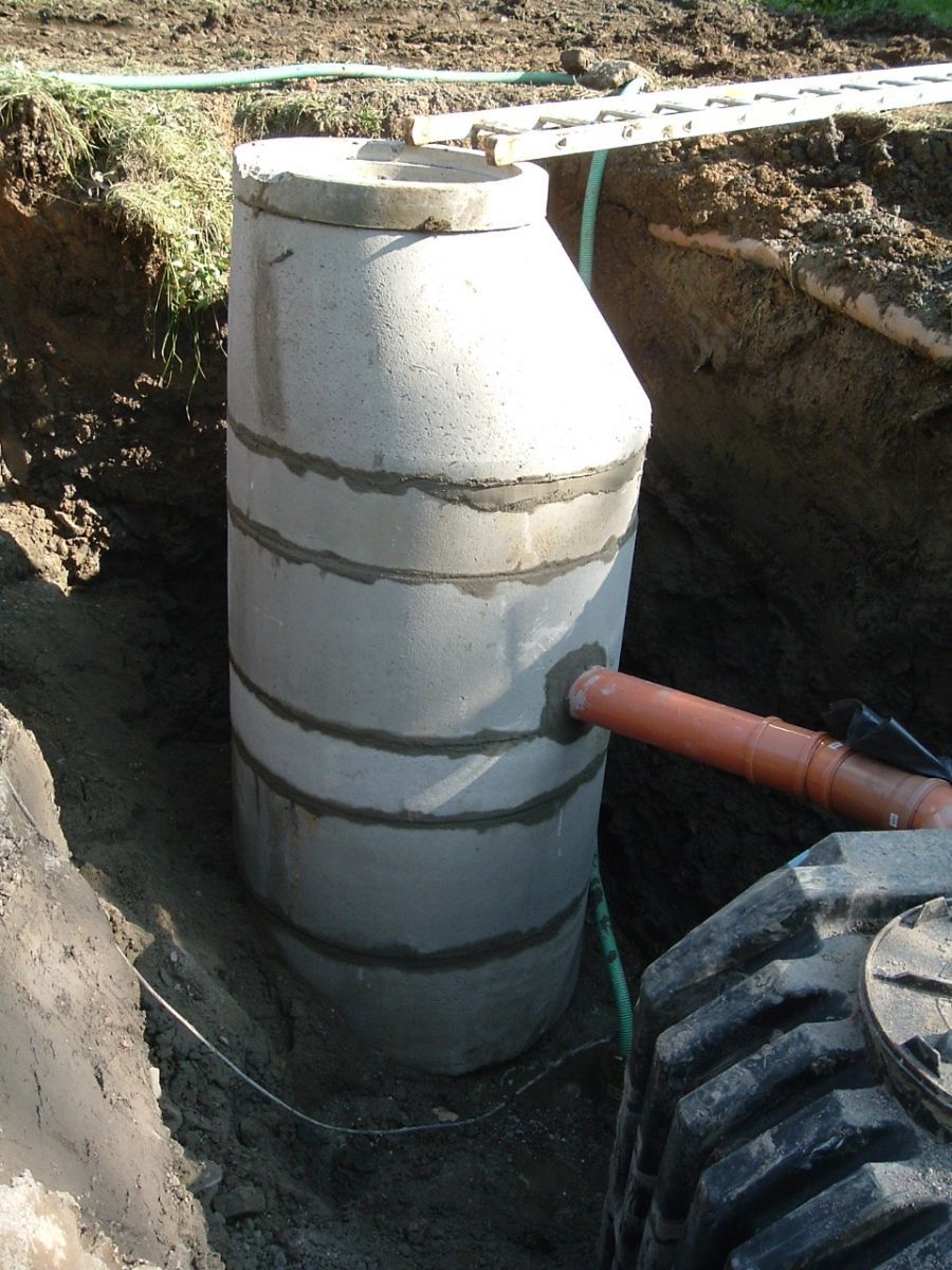 Klärgrube aus Beton in einem ausgehobenen Graben mit angeschlossenem Rohr.