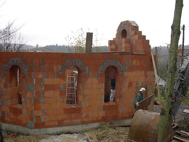 Backsteingebäude im Bau; Arbeiter, Gerüst, bewölkter Tag.
