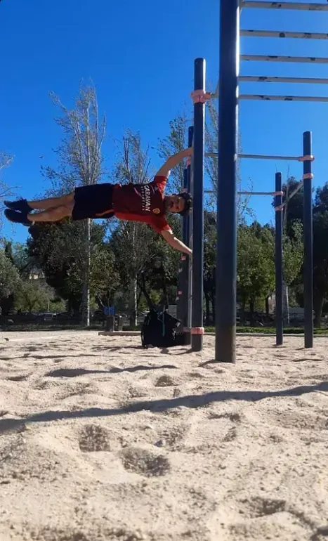 Un hombre está haciendo una parada de manos en una barra en un parque.