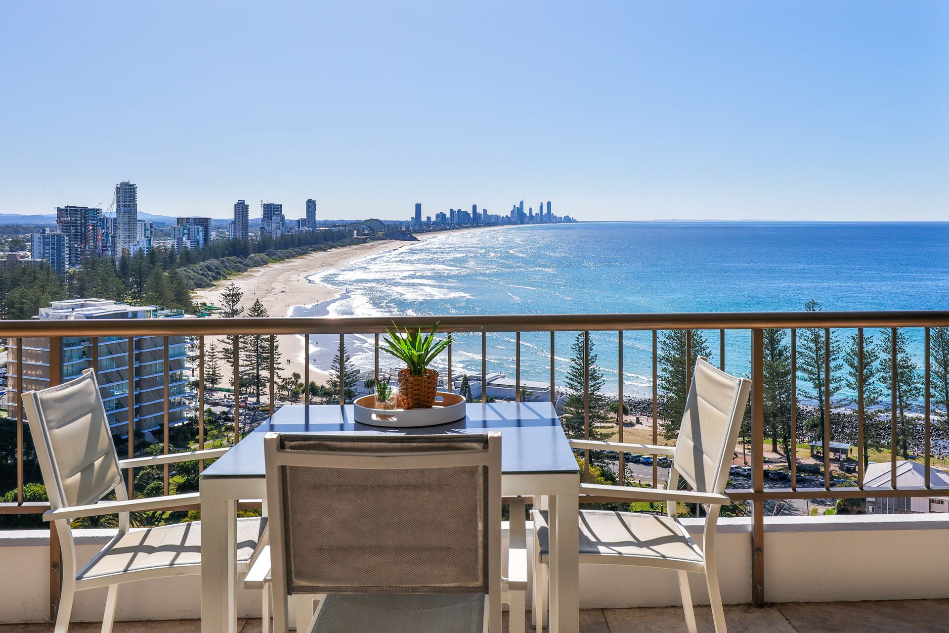 There is a table and chairs on the balcony overlooking the ocean.