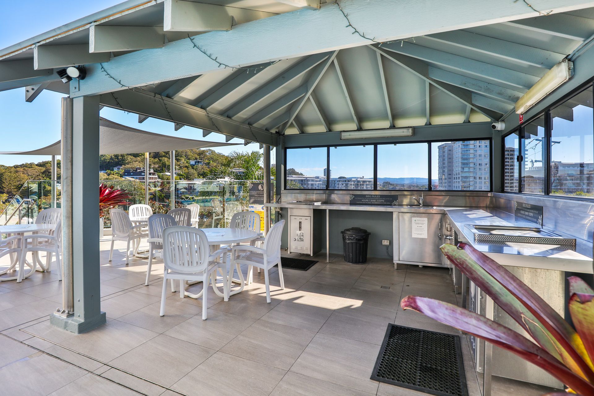 A covered patio with tables and chairs and a kitchen.